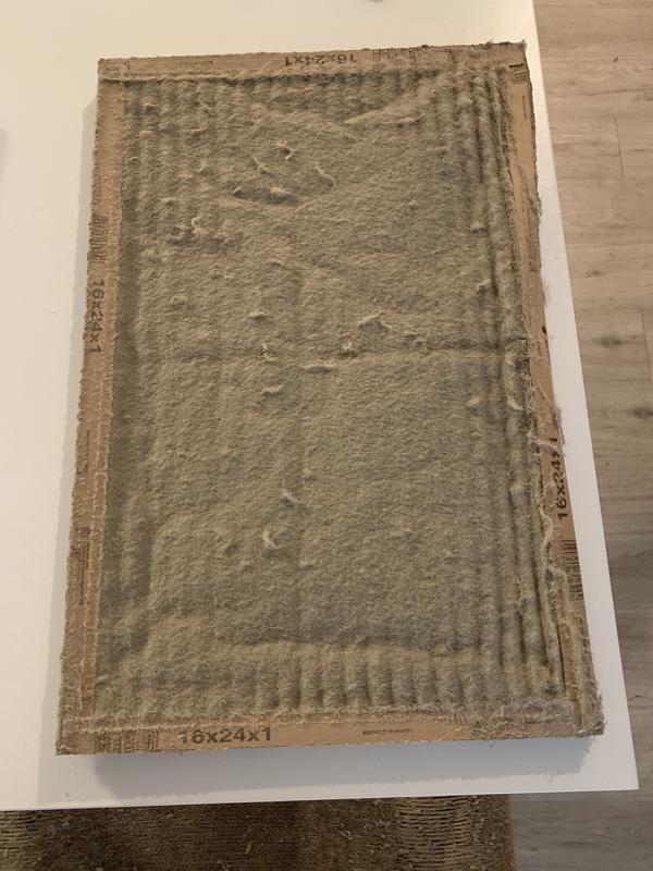 A dirty air filter sitting on a white tabletop.