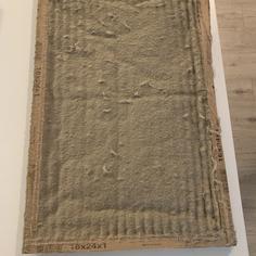 A dirty air filter sitting on a white tabletop.