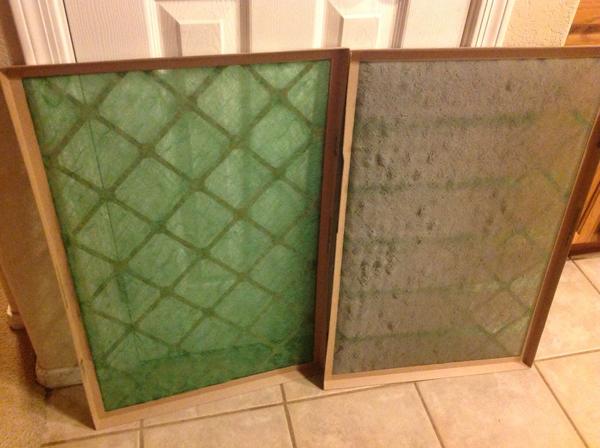 A clean green air filter sitting upright next to an upright dirty air filter.