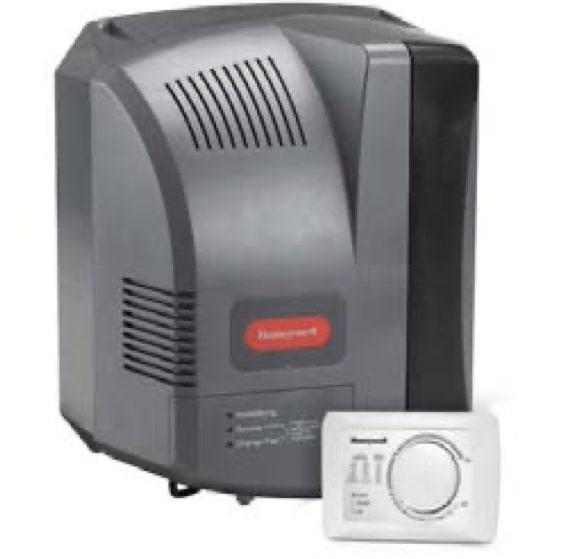 A black Honeywell fan-powered humidifier with its white control panel leaning against it.
