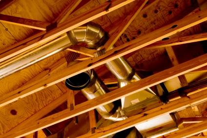 Metal ductwork installed in the wooden rafters of a roof