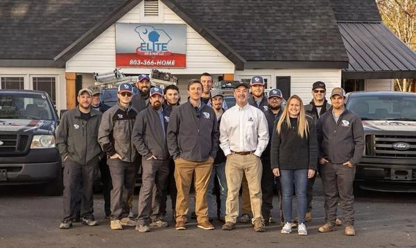 The Elite Air team members gathered for a group photo in front of their office and branded service trucks
