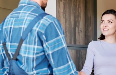 Smiling woman shakes hand of service technican