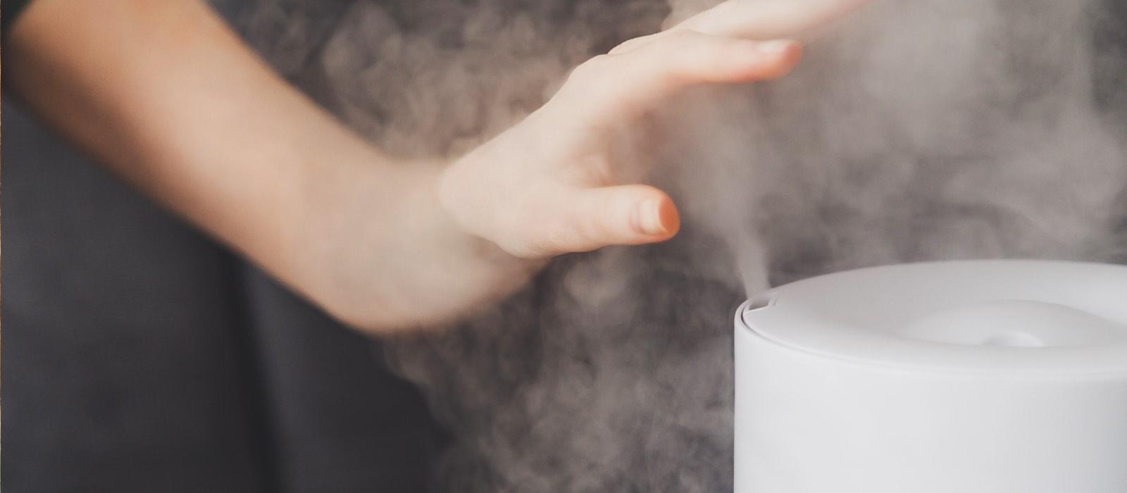 Woman's hand feels mist from humidifier