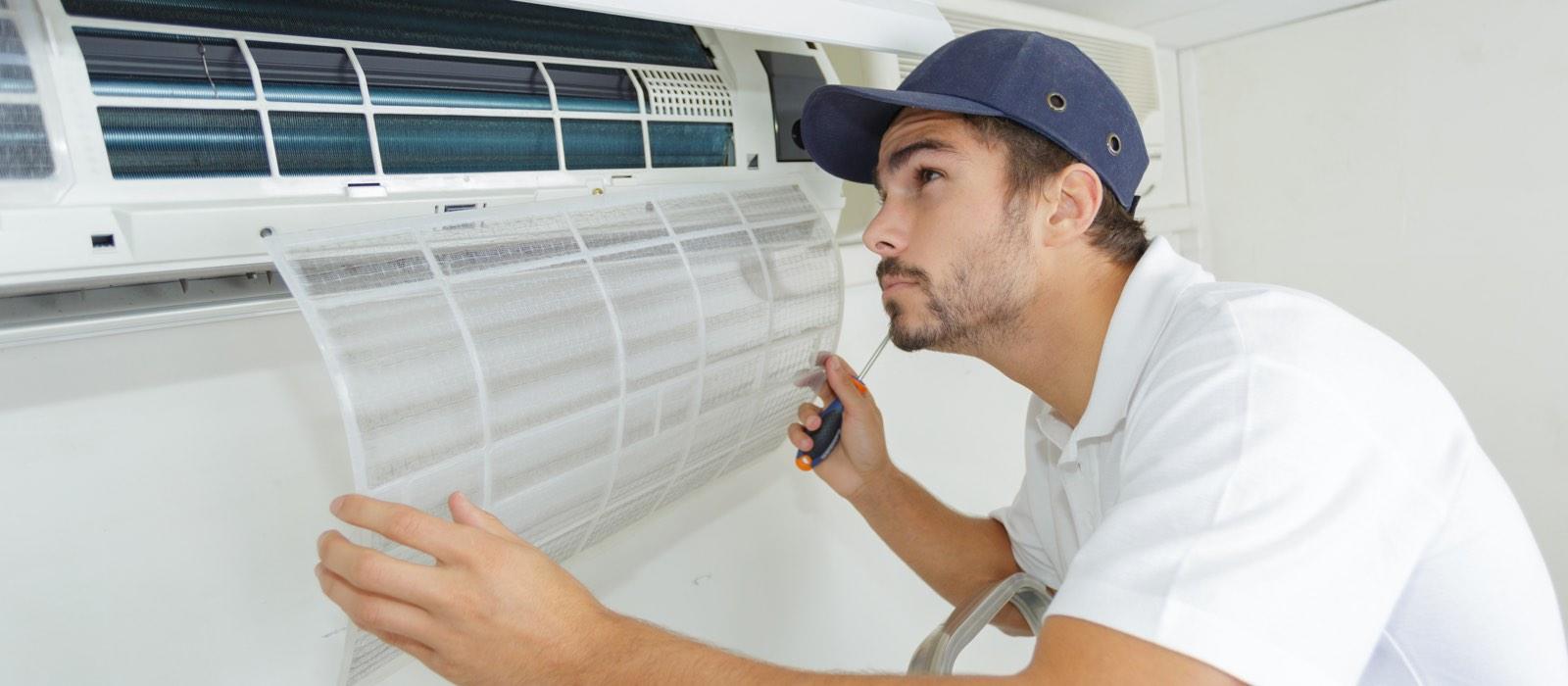 Male technician inspecting ductless AC unit